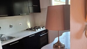 Une cuisine avec des meubles de couleur noire, un plan de travail blanc, une cuisinière à gaz et une fenêtre.