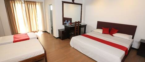 A hotel room with two beds, a desk, a mirror, and a ceiling fan.