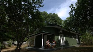 A two-story house with a porch, surrounded by trees. - pavona lake hotel (Sigiriya)