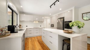 Een moderne keuken met witte kasten, een ingebouwde oven en een roestvrijstalen koelkast.