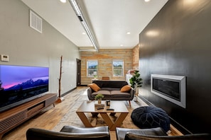 A modern living room with a flat-screen TV, a sofa, a coffee table, and a fireplace.