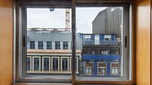 Una finestra con vista su un edificio multipiano e una gru sullo sfondo.