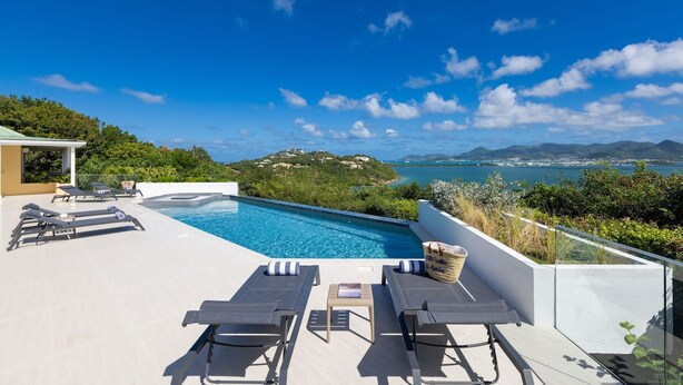 A rooftop infinity pool with lounge chairs and a view of the sea and hills. - Villa OSUN (Les Terres Basses)