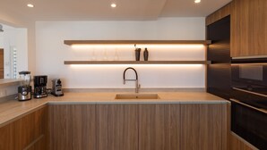 A modern kitchen with wooden cabinetry, a built-in sink, and a Bosch refrigerator. - Villa OSUN (Les Terres Basses)