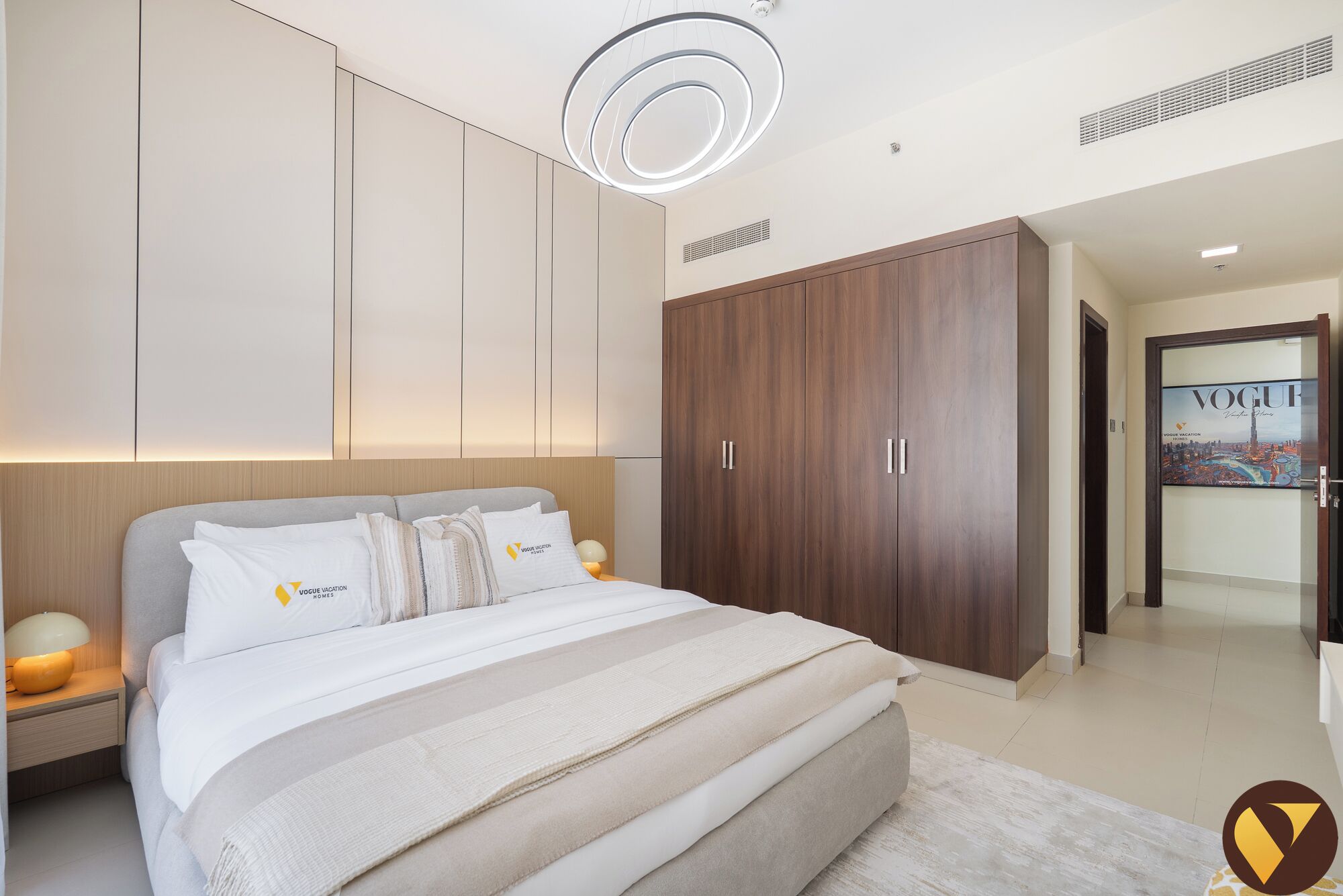 Ein modernes Schlafzimmer mit einem großen Bett, einem Holzschrank und einer Deckenleuchte.