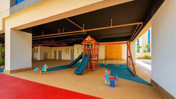 Un espace de jeux pour enfants avec un toboggan, une structure d’escalade et une balançoire.