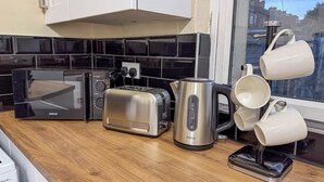 A kitchen with a black microwave, a silver toaster, a stainless steel kettle, and a mug rack with white mugs. - Family/business - Parking - Wifi - Sleeps 3 (Barnsley)