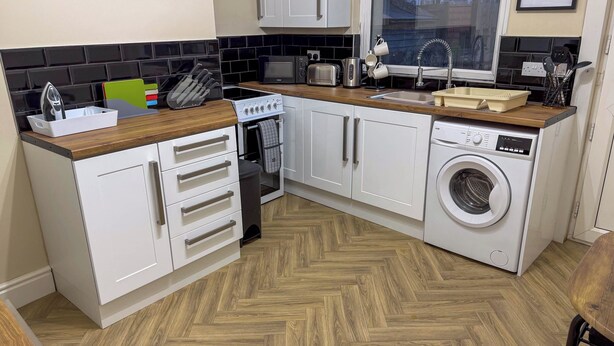 A compact kitchen with white cabinets, a built-in oven, a microwave, a toaster, and a washing machine. - Family/business - Parking - Wifi - Sleeps 3 (Barnsley)
