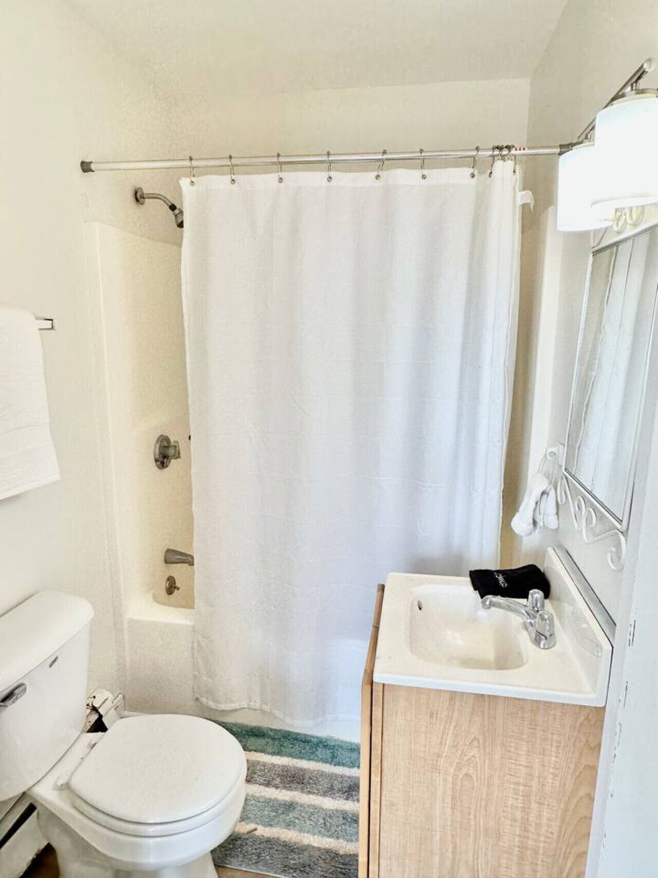 A small, clean bathroom with a toilet, sink, and shower.