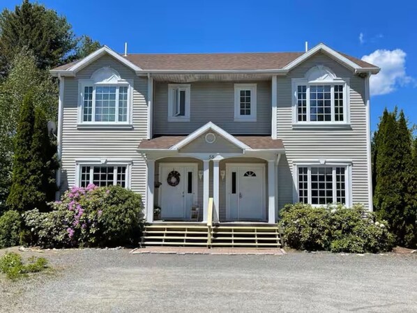 Une maison à deux étages avec un porche à l’avant, un garage et une allée.