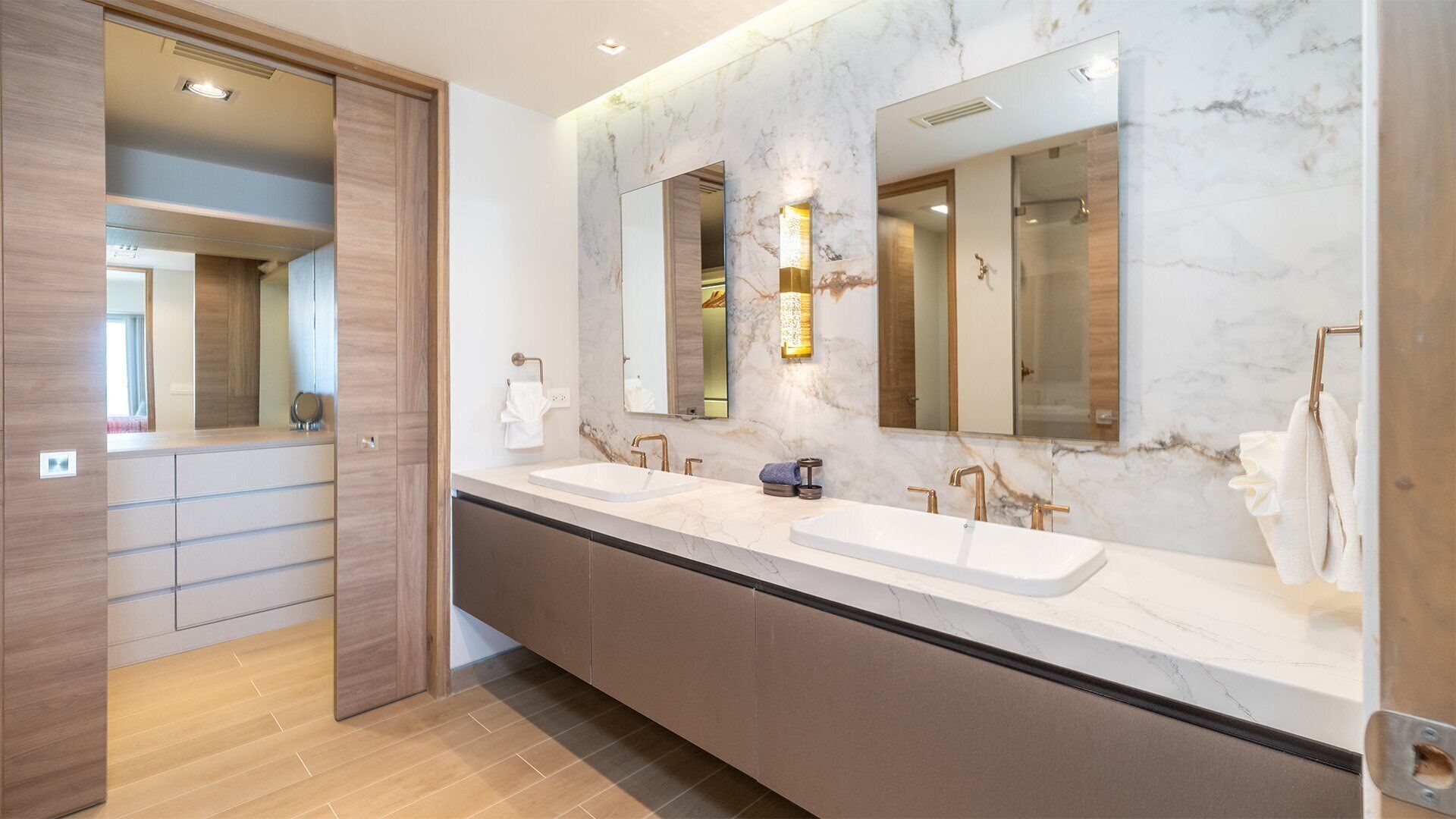 Un baño moderno con dos lavamanos, salpicadero de mármol y un espejo grande.