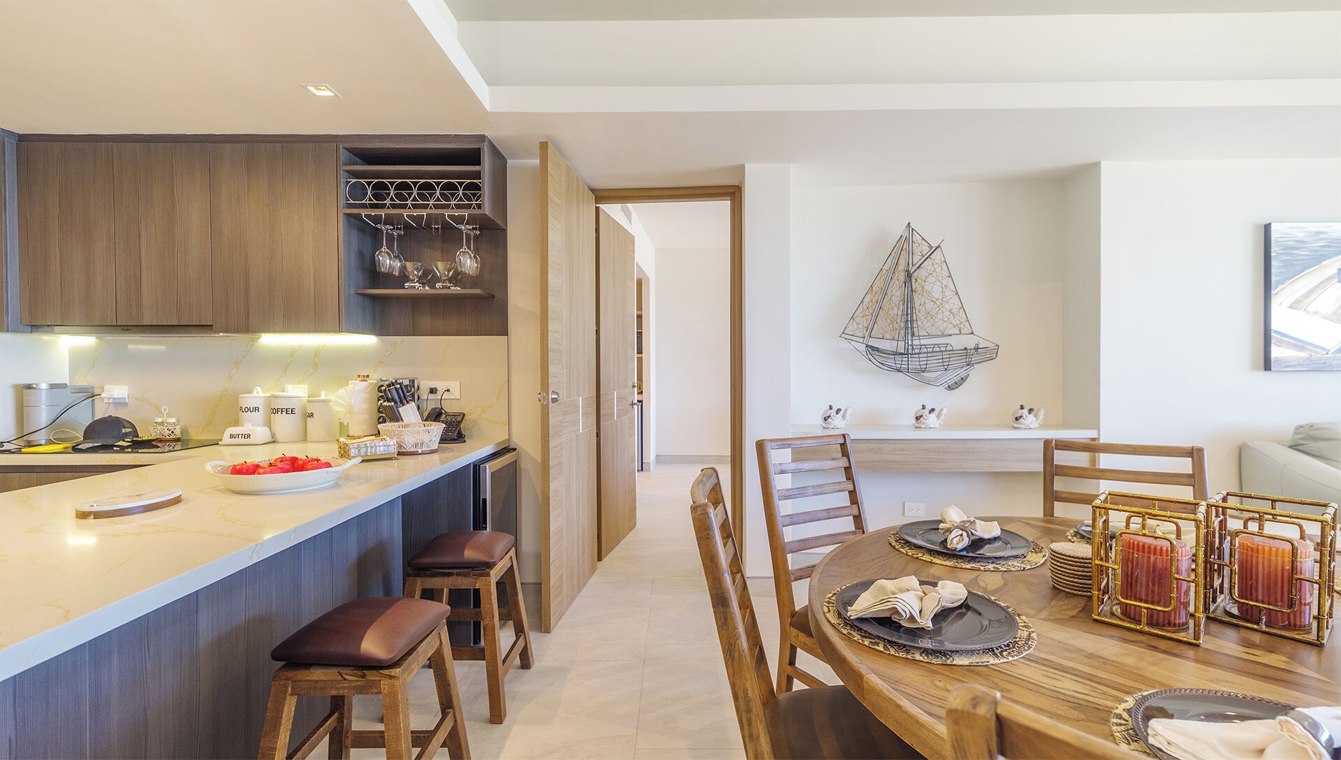 Una cucina moderna con mobili in legno, un piano di lavoro in marmo e una zona pranzo con tavolo e sedie in legno.