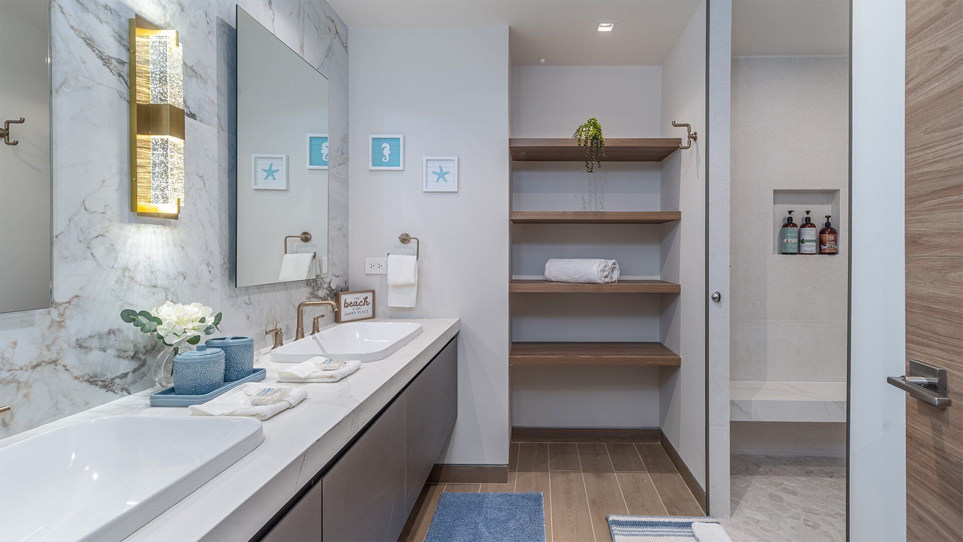 Une salle de bain moderne avec un meuble-lavabo en marbre, un grand miroir et un espace douche doté d’étagères en bois.