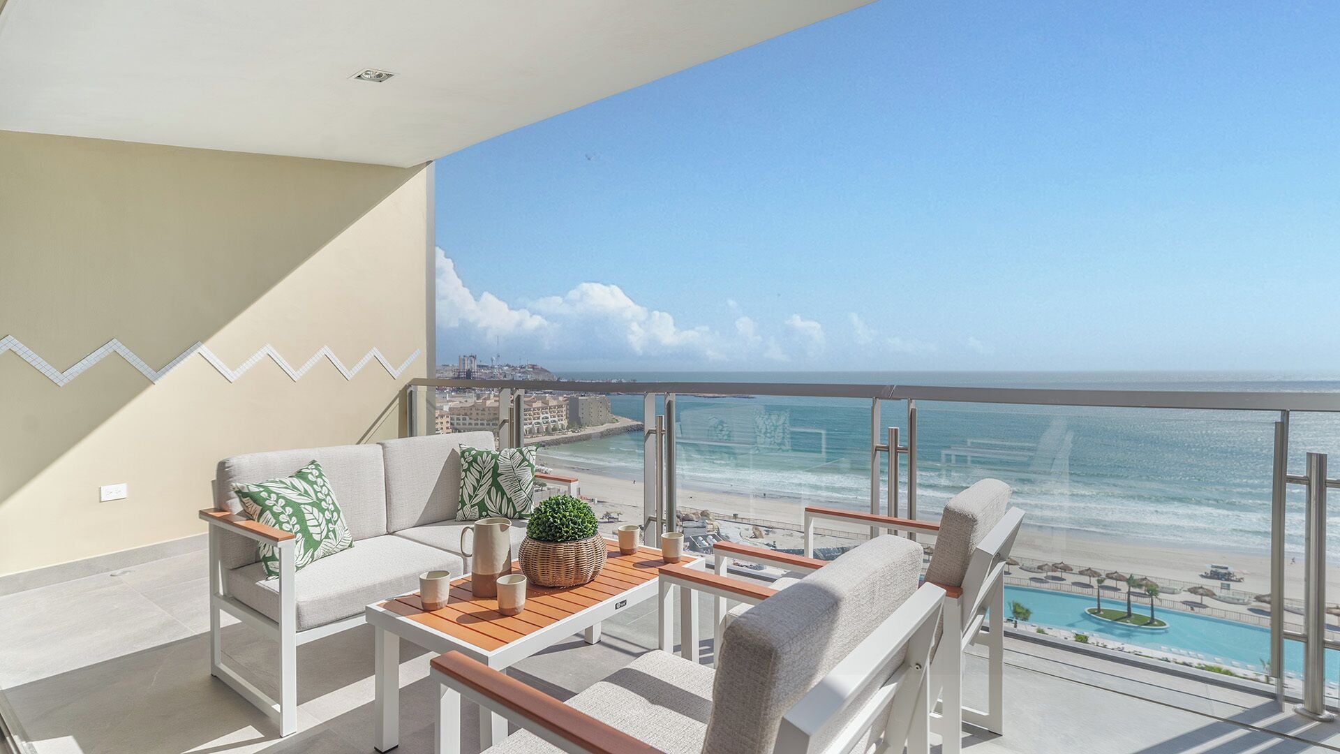 Een balkon met uitzicht op de oceaan, een bank, een bijzettafeltje en een stoel.