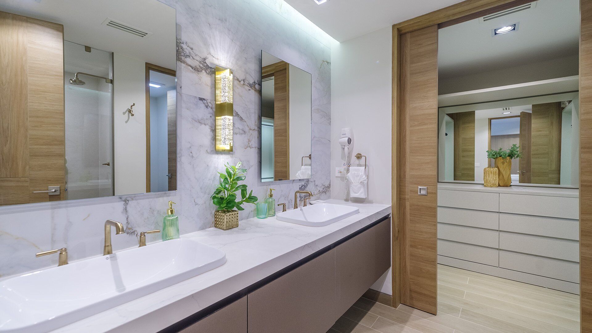 Ein modernes Badezimmer mit zwei Waschbecken, einem großen Spiegel und einem Föhn.