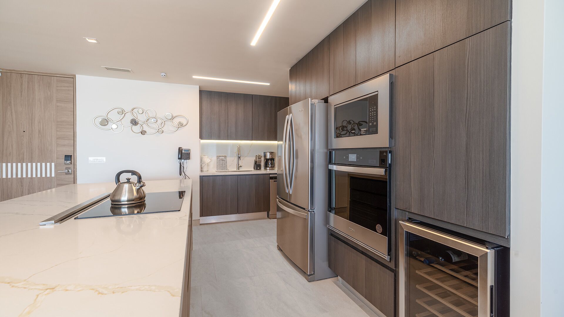 Una cucina moderna con isola centrale, elettrodomestici integrati e un elemento decorativo a parete.