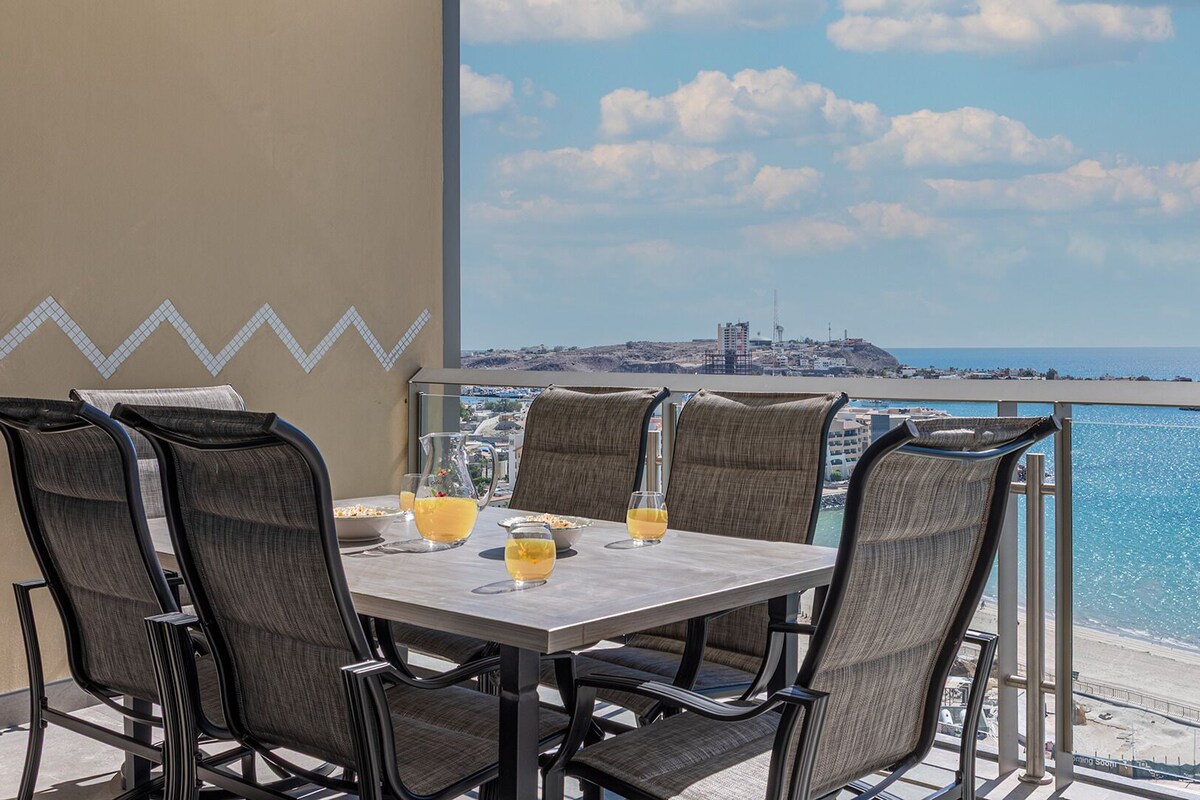 Un coin repas avec une table et des chaises, une carafe de jus d’orange et un verre de jus d’orange.