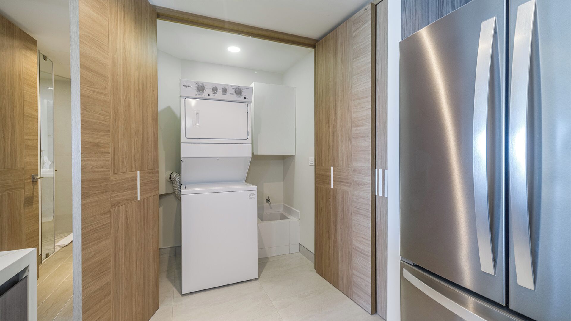Eine kompakte Küche mit Edelstahlkühlschrank, Backofen und Waschmaschine.