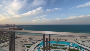 Un hotel sulla spiaggia con area piscina, vista sull'oceano e sullo skyline urbano sullo sfondo.
