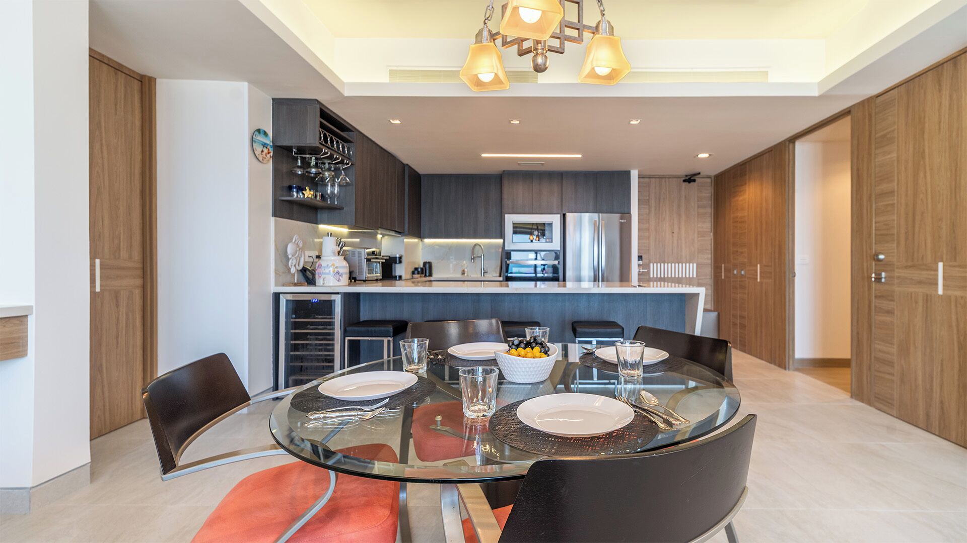 A modern kitchen with a central island, built-in appliances, and a dining area with a glass table and chairs.