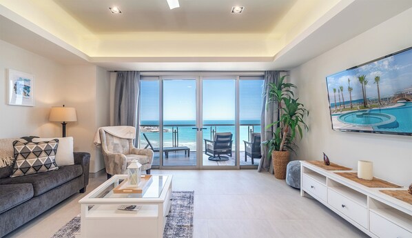 Ein geräumiges Wohnzimmer mit einem großen Schiebeglasfenster, das auf einen Balkon mit Meerblick führt.
