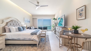A bedroom with a bed, a desk, a chair, a balcony with a view, and a ceiling fan. - Sonoran Star One (Puerto Peñasco)