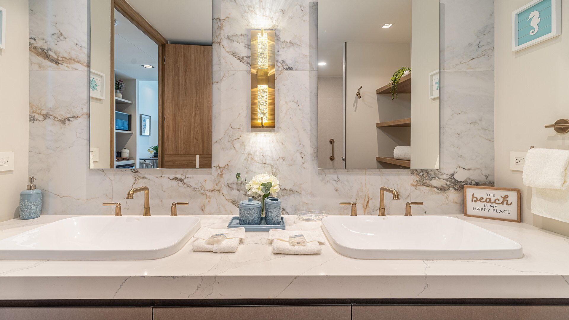 A modern bathroom with two sinks, marble countertops, and a decorative light fixture.