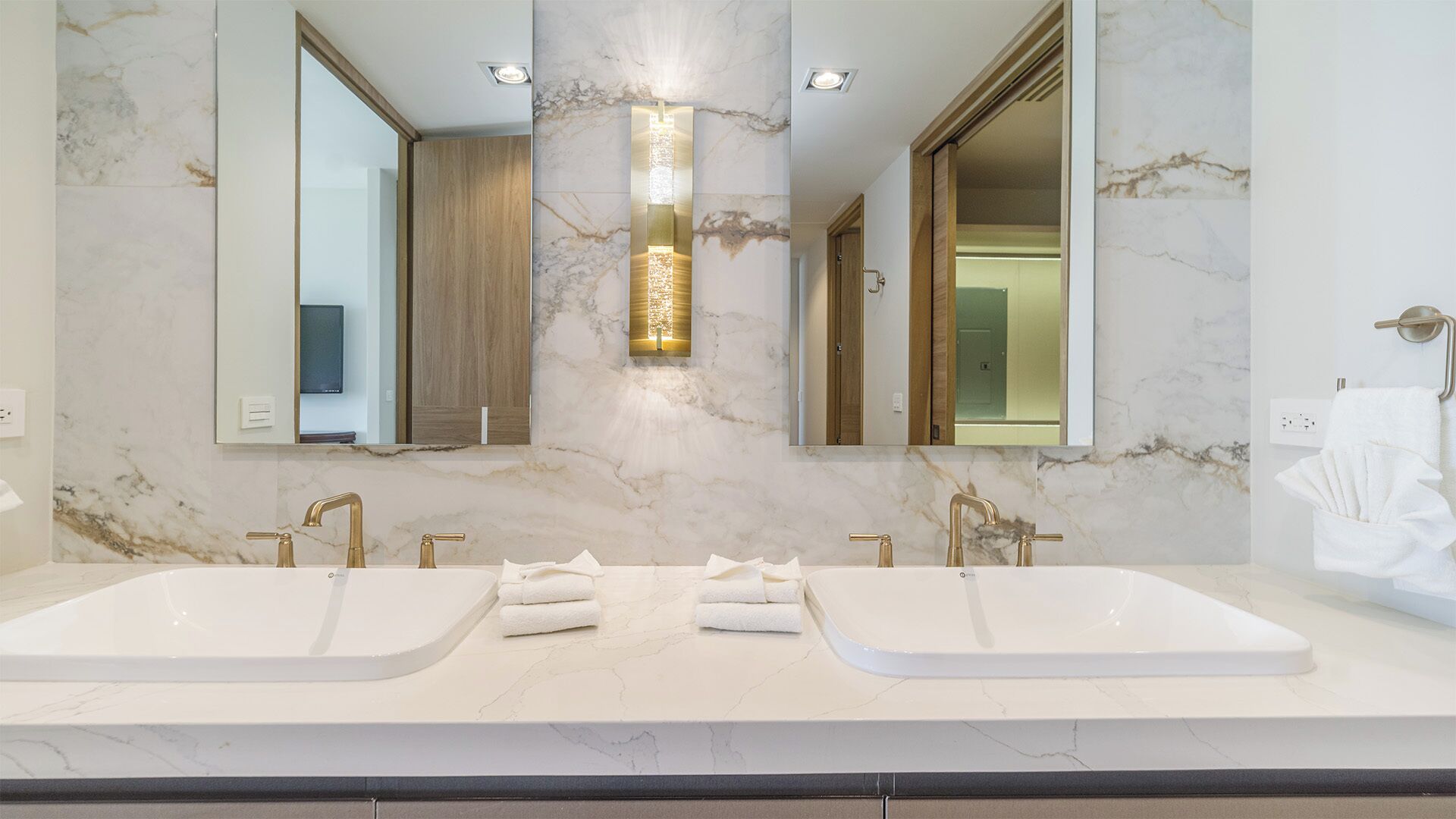 Un baño moderno con dos lavamanos, un espejo grande y una lámpara vertical.
