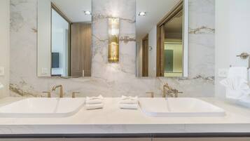 Un baño moderno con dos lavamanos, un espejo grande y una lámpara vertical.