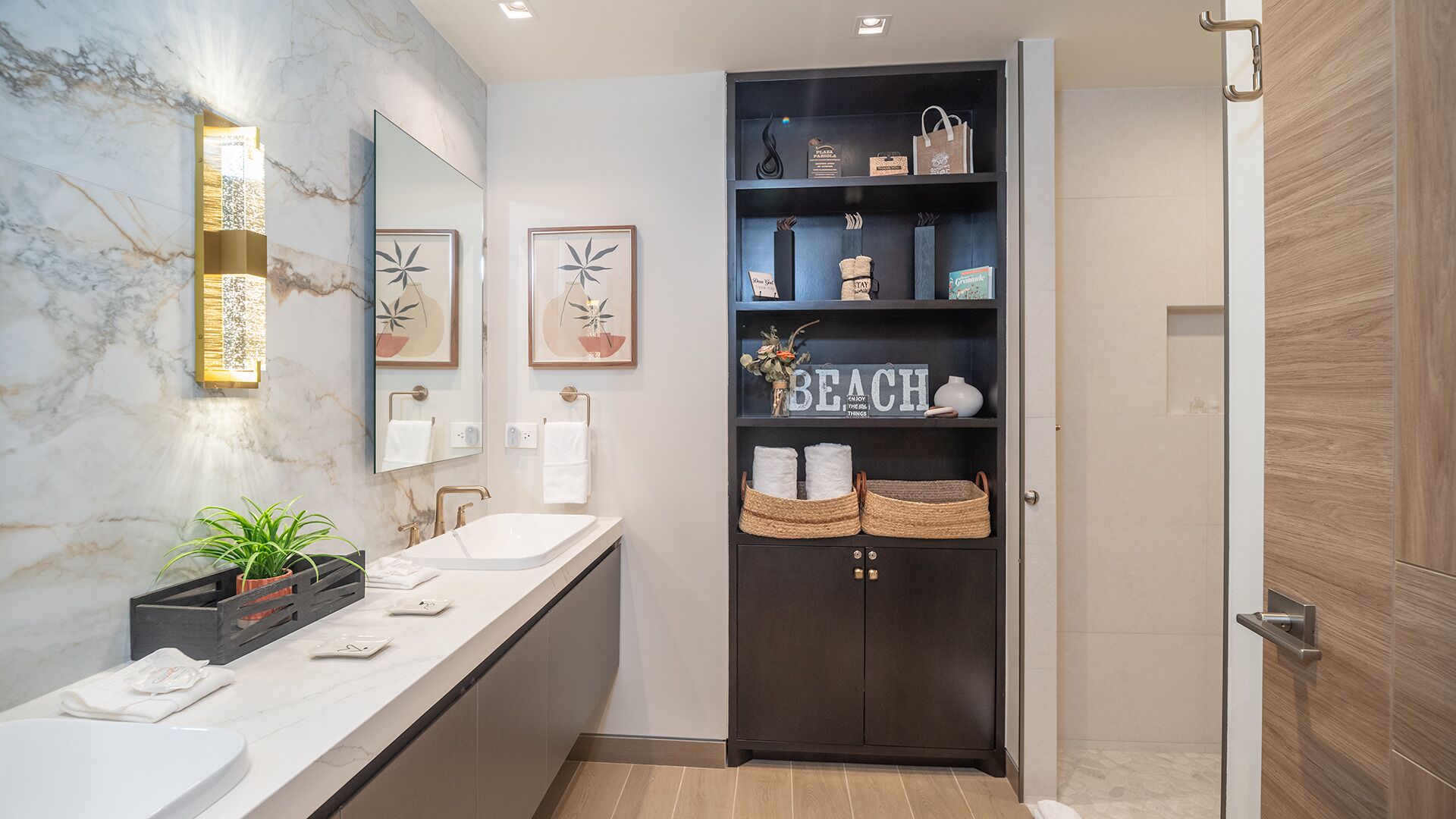 A modern bathroom with two sinks, a large mirror, and a dark wooden cabinet with shelves.