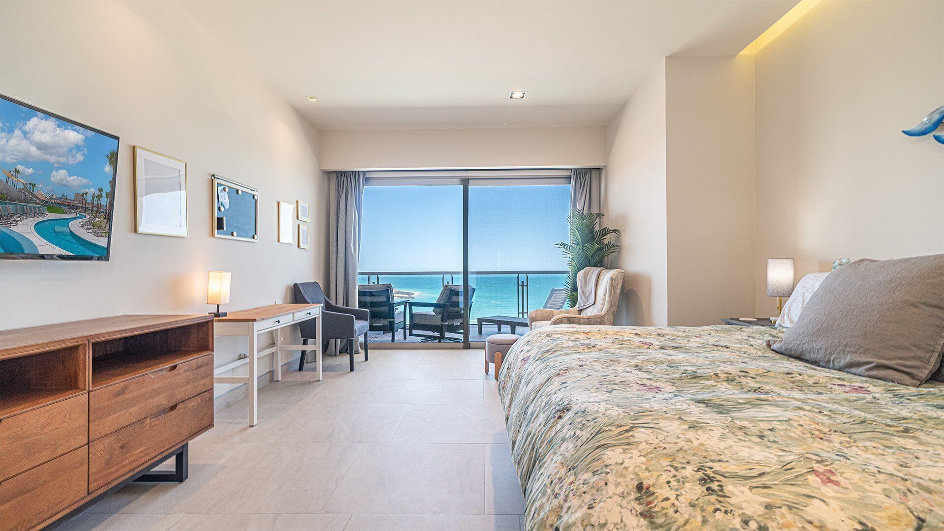 Ein Hotelzimmer mit Bett, Schreibtisch, Stuhl, Fernseher und Meerblick.