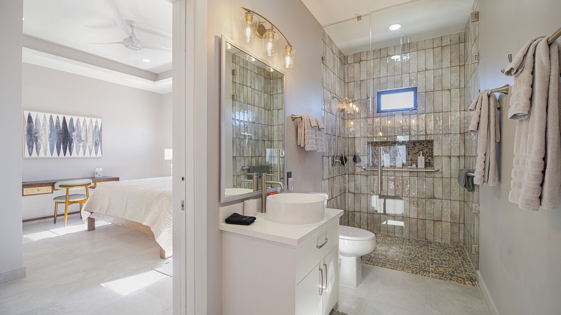 A modern bathroom with a large mirror, a sink, a toilet, and a shower area.