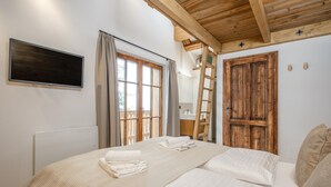 A bedroom with a wooden ceiling, a bed with white linens, a window with curtains, and a wooden door. - Chalet on the Katschberg with sauna (Katschberg)