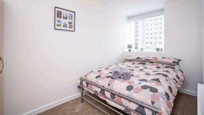 A bedroom with a bed, a window, and a wall-mounted picture.
