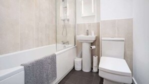 A modern bathroom with a glass-enclosed shower, a white sink, and a toilet.