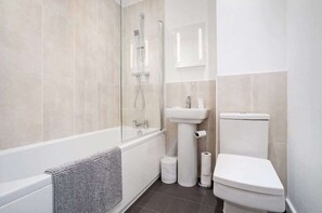 Ein modernes Badezimmer mit einer Duschkabine, einem weißen Waschbecken und einer Toilette.