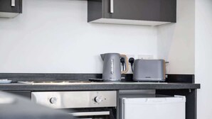 A kitchen with a built-in oven, a toaster, and a kettle on the countertop.