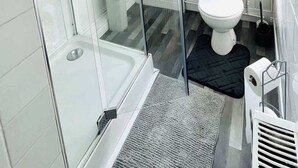 A modern bathroom with a glass-enclosed shower, a white sink, a toilet, and a window with blinds. - Southsea Getaway: Close to Beach & Family Fun! (Portsmouth)