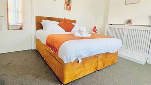 A neatly made bed with a wooden headboard, white bedding, and an orange throw blanket. - Southsea Getaway: Close to Beach & Family Fun! (Portsmouth)