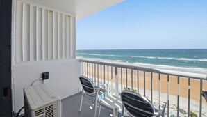 Ein Balkon mit Meerblick, weißen Geländern und zwei Stühlen.