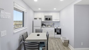 Una cucina moderna con mobili bianchi, un forno a microonde, un piano cottura e una finestra con vista sulla città.