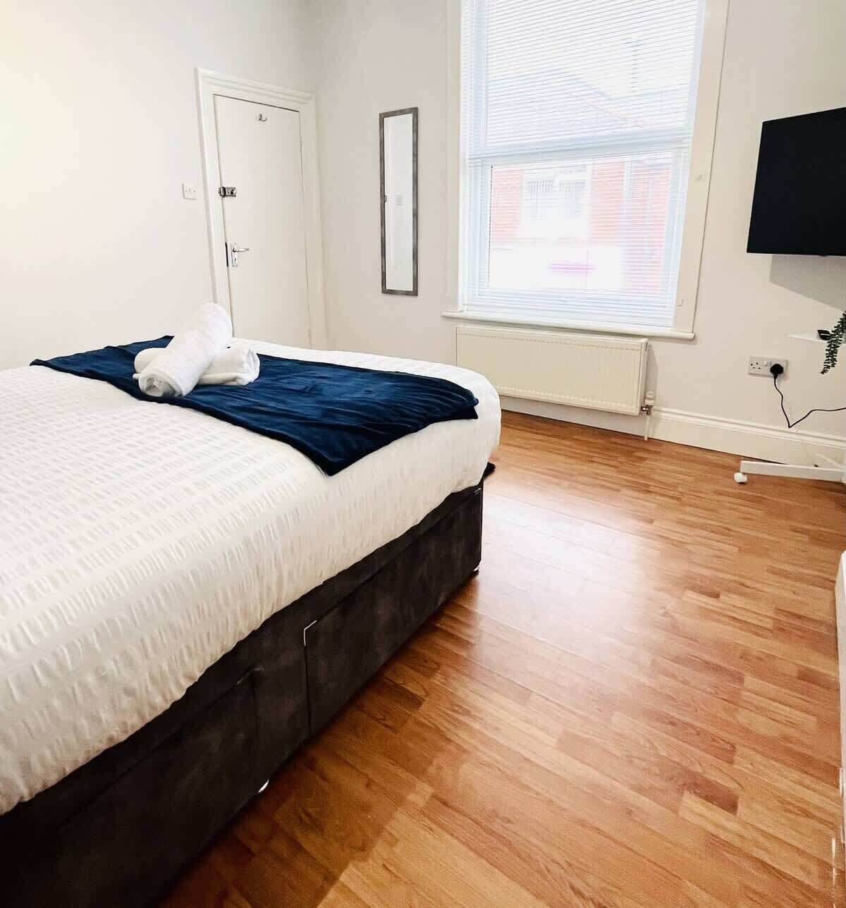 Une chambre à coucher avec un lit, une fenêtre, une porte et un téléviseur fixé au mur.