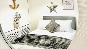 A bed with a gray headboard, white bedding, and a patterned throw blanket. - Portsmouth Apartment: Family friendly with Parking (Portsmouth)