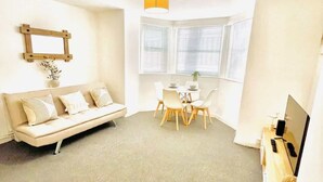 A modern living room with a sofa, dining table, chairs, and a TV. - Portsmouth Apartment: Family friendly with Parking (Portsmouth)