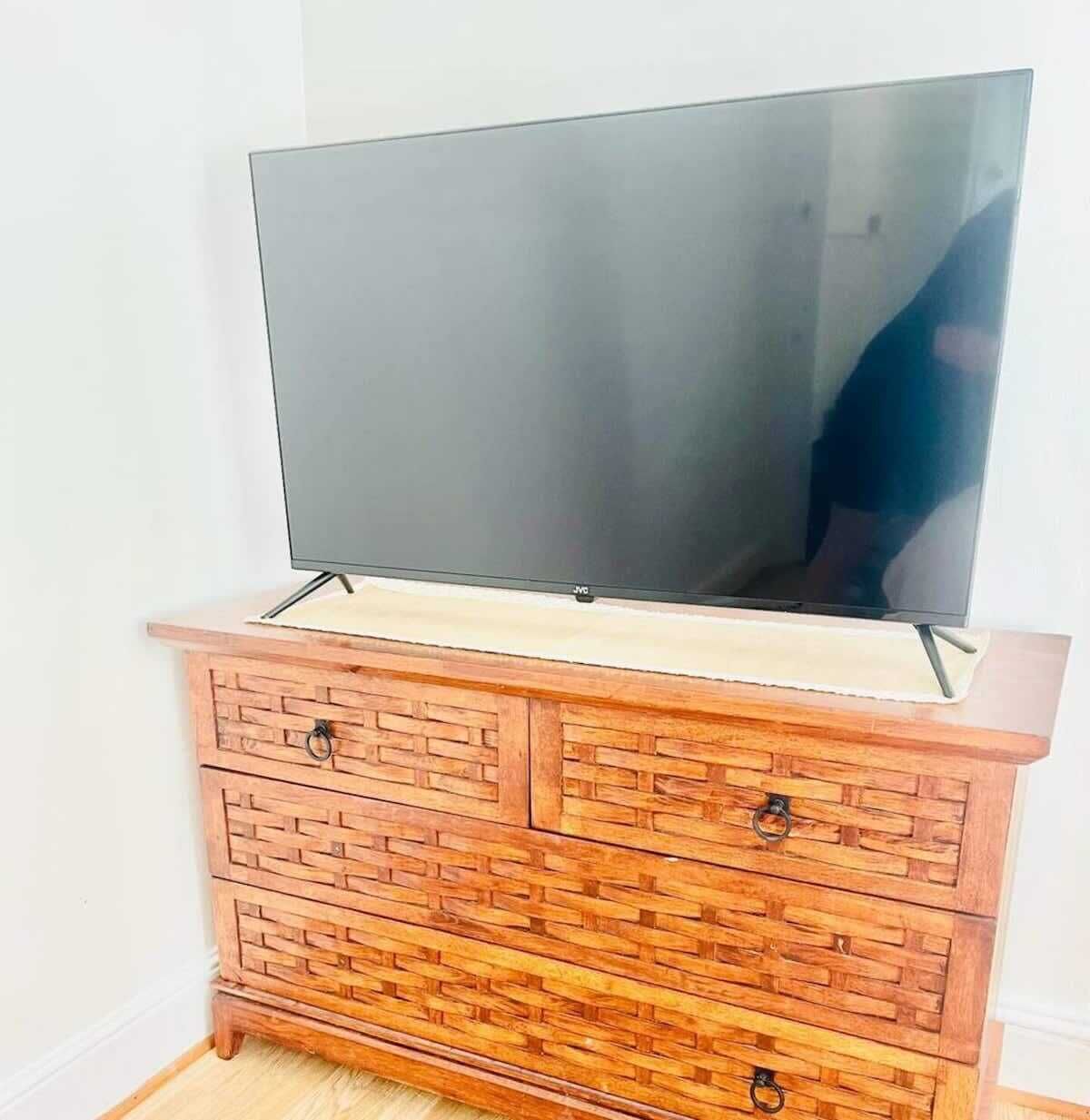 Un téléviseur à écran plat posé sur une commode en bois dotée de tiroirs.