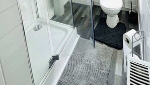 Ein modernes Badezimmer mit einer einteiligen Duschkabine, einem weißen Waschbecken und einer Toilette.