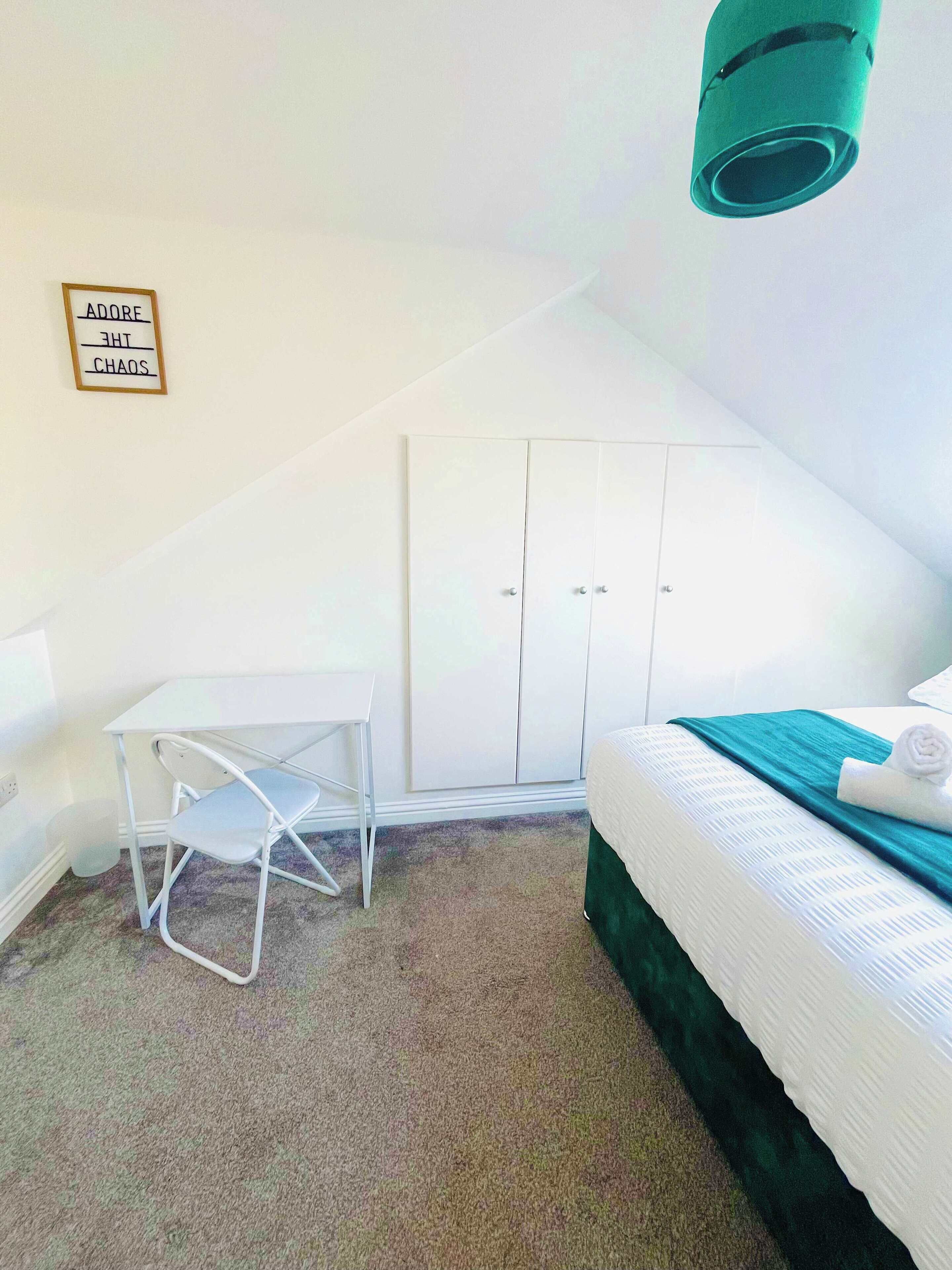 Een kleine, net kamer met een bed, een bureau en een kledingkast.