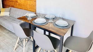 A dining area with a wooden wall, a round clock, and a modern table set for four. - Cleveland Road House: Comfort & Convenience (Portsmouth)