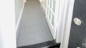 A narrow hallway with a carpeted floor, a white door with glass panels, and a staircase in the background. - Clarence Road: Cozy King Room in Portsmouth (Portsmouth)