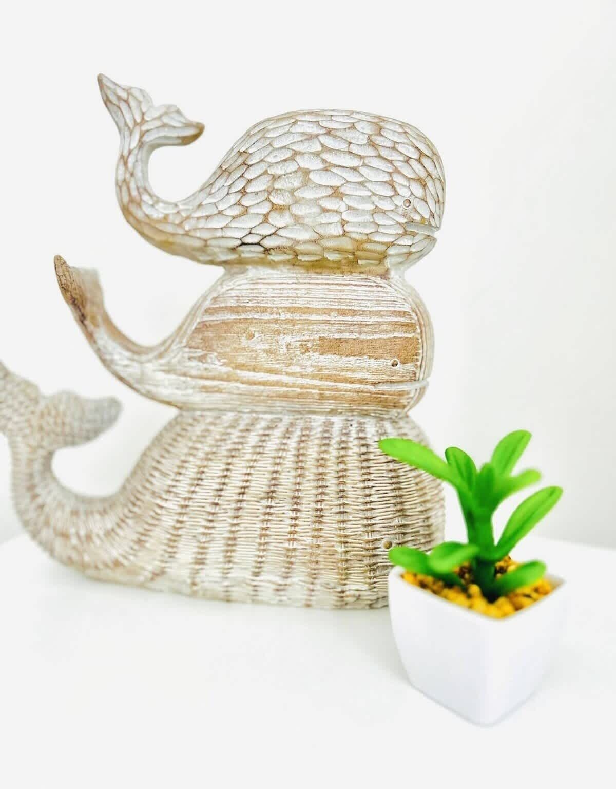 Een decoratieve walvissculptuur met een structuurrijk oppervlak en een bloempot ernaast.